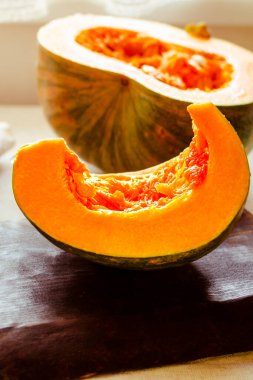 Balkabağı, balkabağı parçalarına ayrılmış kabak, bıçak, tahta kaşık, masada demir kap, kırsal kumaş.