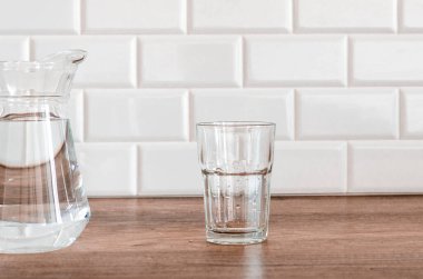 Beyaz arka planda su olan sürahi ve cam. Mutfakta.