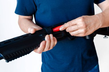 Adam tüfeği cephaneyle dolduruyor. Pompa delikli silahı şarj ediyorum. Yakın plan fotoğraf..