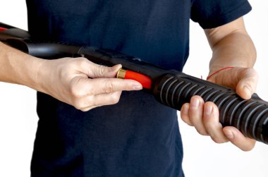 Adamın silahının şarjörüne kırmızı bir av tüfeği kovanını doldurduğu yakın plan. Pompayı şarj ediyorum.