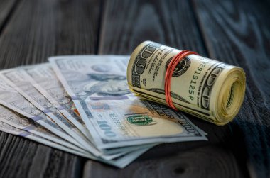 Masadaki diğer banknotların üzerine bir tomar para ve para. Yüz dolarlık banknotun altını çiz..