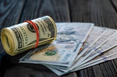 Masadaki diğer banknotların üzerine bir tomar para ve para. Yüz dolarlık banknotun altını çiz..