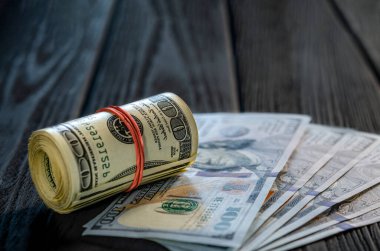 Masadaki diğer banknotların üzerine bir tomar para ve para. Yüz dolarlık banknotun altını çiz..