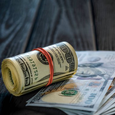 Masadaki diğer banknotların üzerine bir tomar para ve para. Yüz dolarlık banknotun altını çiz..