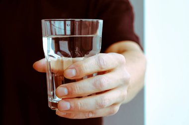 Su dengesi. Bir adamın eli bir bardak saf kaynak suyuyla