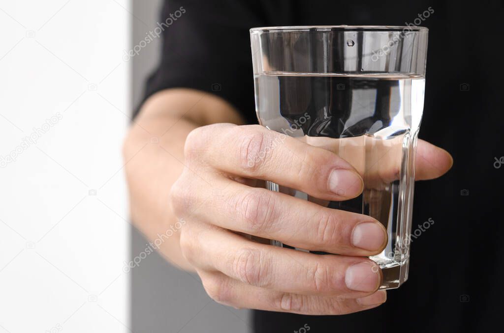 A glass with clean melted water in the hand of a man. Water balance