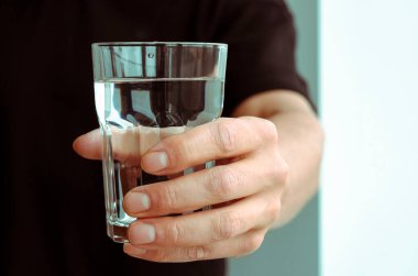 Bir adamın elinde bir bardak saf erimiş su. Sağlığa. Su dengesi