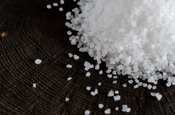White large crystals of salt scattered on a wooden background
