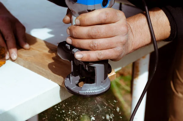 closeup of carpenter with hand wood router machine at work. closeup of routing a bevel into plank of pine woodworking construction tool concept furniture making diy background