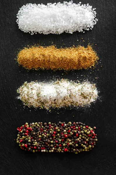 variety of natural and spicy salt on black table. Kitchen background