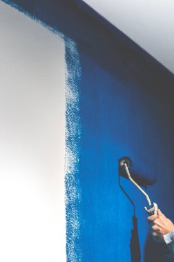 Tamir et. Maviyle beyaz bir duvar boyuyor