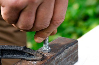 Adamın biri metal bir fındığa vida sokuyor. Metalle çalışmak