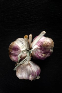 Siyah arka planda sarımsak soğanı ve sarımsak karanfili. Yakın çekim, düz yatış, üst manzara. Gıda arka planı, seçici odak.