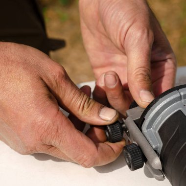 Yakından bir adamın elleri. Bir adam bir değirmen makinesini tamir eder.