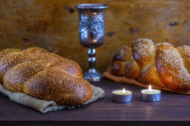 Şabat Şalom - Challah ekmeği, Şabat şarabı ve kahverengi ahşap masadaki mumlar.