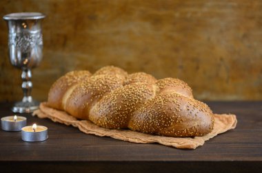 Şabat Şalom Challah ekmeği, Şabat şarabı ve kahverengi ahşap masada mumlar..