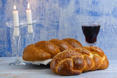 Şabat Şalom - Challah ekmeği, Şabat şarabı ve mavi arka plandaki ahşap masa üzerindeki mumlar.