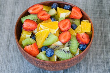 Gri arka planda kahverengi kasede sağlıklı taze meyve salatası. Üst Manzara. Kapat..