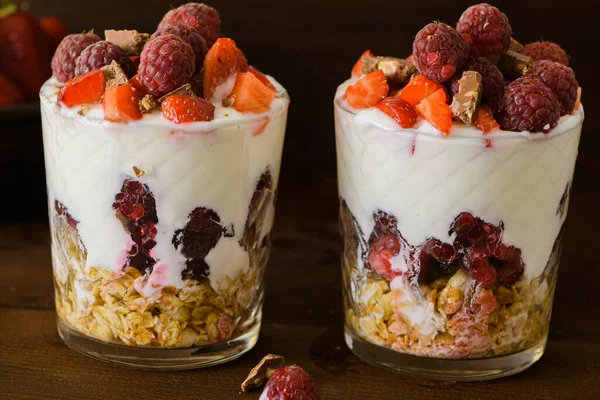 Taze böğürtlenli ve müsli bardakta doğal Yunan yoğurdu. Sağlıklı yemek, sağlıklı yaşam tarzı, spor fitness beslenme menüsü konsepti. Kahverengi arka planda.