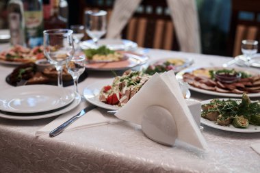 Lezzetli aperatifler ve atıştırmalıklarla dolu bir şölen masası. Restoranda süslü bardaklar ve gümüş çatal bıçaklarla servis edilen bayram ziyafeti. Düğün doğum günü partisi kutlaması.