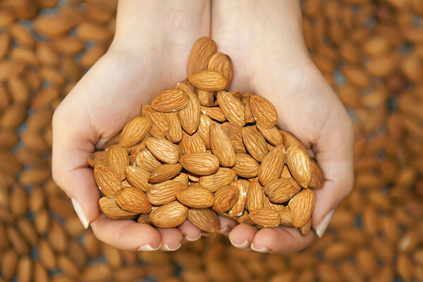 Almond in hands shaping heart