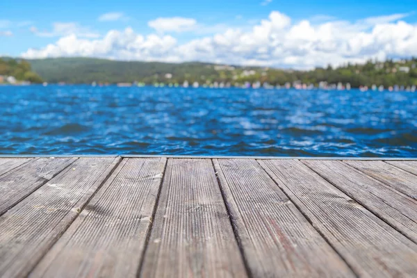 Ahşap masa üstü, bulanık göl manzaralı ve bulanık arkaplan. Ürün sergisi arka plan konsepti. Bulutlu mavi gökyüzü.