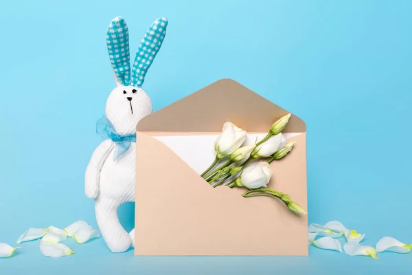 Delicate postcard layout of white flowers and bunny blue background. Holiday flat lay congratulations. — Stockfoto