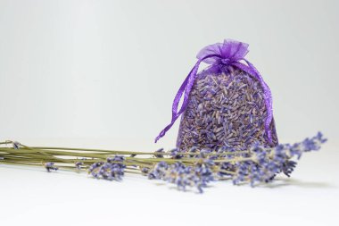 Kuru buketin yanında lavanta tohumları olan küçük mor bir çanta..