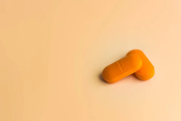 Δύο Μεγάλα Πορτοκαλί Χάπια Ένα Απαλό Πορτοκαλί Φόντο Επιλεκτική Εστίαση — Φωτογραφία Αρχείου