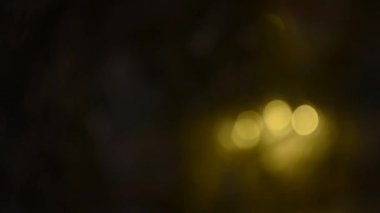 Penceredeki karanlık bir odada yılbaşı çelenkleri yanıp sönüyor. Fesif bulanık arkaplan. Arkaplan