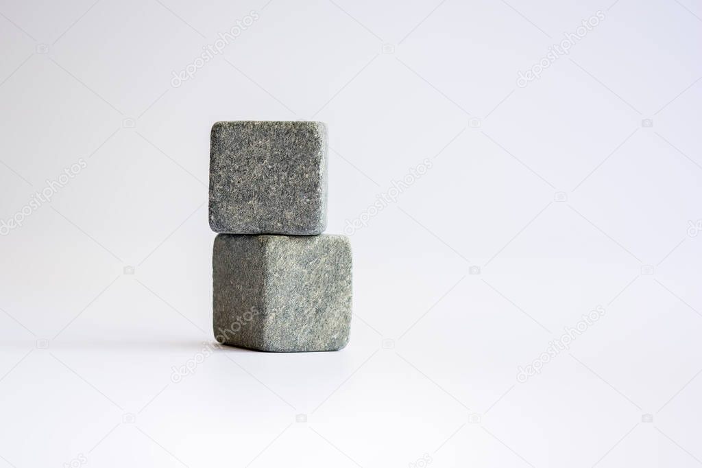 Two stone cubes one above the other. Whiskey stones on a white background.