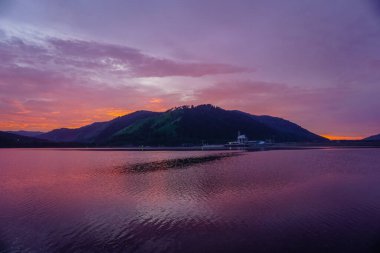 Beautiful Sayan mountains in the reflection of the Yenisei river at sunset clipart