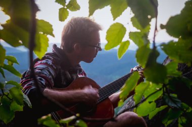 Adam gün batımında Krasnoyarsk sütunlarında gitar çalıyor.