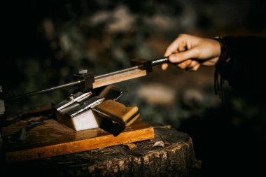 Klasik mutfak bıçağı bileme makinesi ve genç bir ustanın eli.