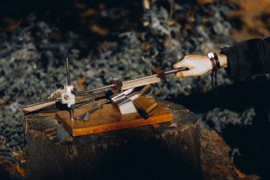 Klasik mutfak bıçağı bileme makinesi ve genç bir ustanın eli.