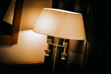 Komodinin üzerinde beyaz bir gölge olan bir lamba.