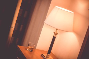 Komodinin üzerinde beyaz bir gölge olan bir lamba.