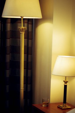 Komodinin üzerinde beyaz bir gölge olan bir lamba.