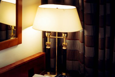 Komodinin üzerinde beyaz bir gölge olan bir lamba.