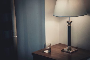 Komodinin üzerinde beyaz bir gölge olan bir lamba.