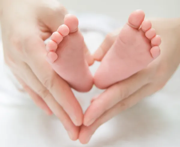 Nyfödd baby fötter på kvinnliga händer — Stockfoto