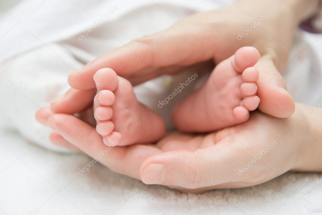 Newborn baby feet on a female hand