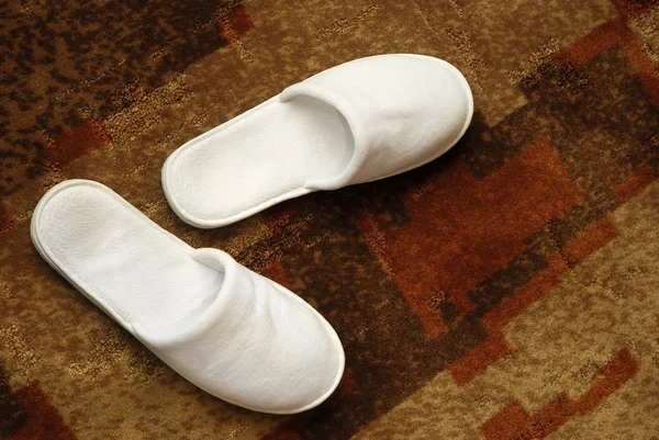 Dvojice bílé pantofle na koberec — Stock fotografie