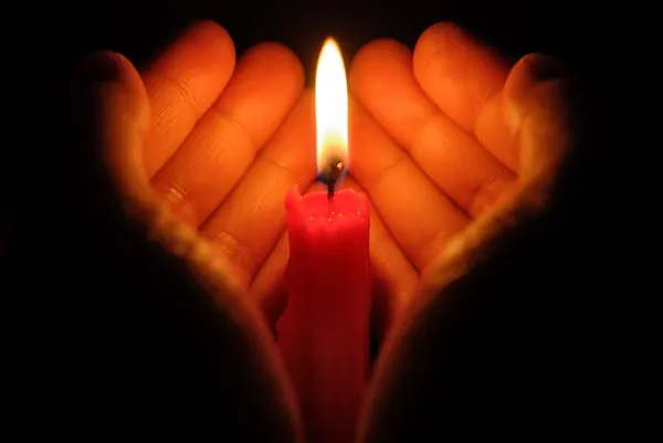 Mãos segurando uma vela acesa no escuro Fotos De Bancos De Imagens