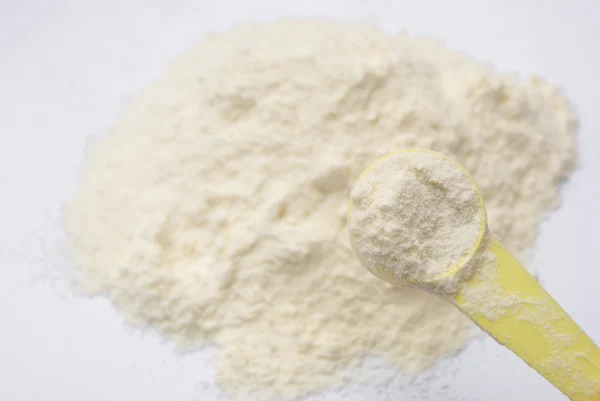 Latte in polvere e cucchiaio giallo — Foto Stock