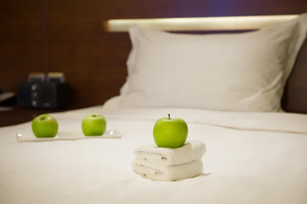 Manzanas y toallas en la cama en una habitación de hotel — Foto de Stock