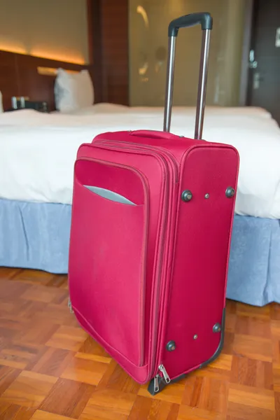 Maleta roja se levanta dentro de una habitación de hotel —  Fotos de Stock