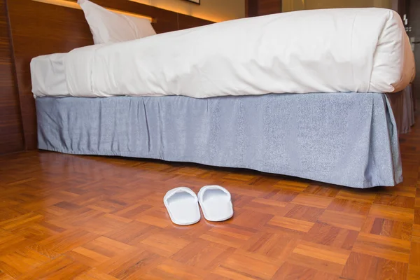 Pantoufles et lit dans une chambre d'hôtel — Photo