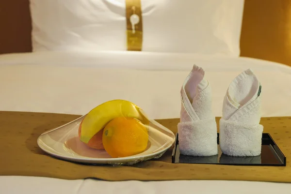 Handdoeken en fruit op bed in een hotelkamer — Stockfoto