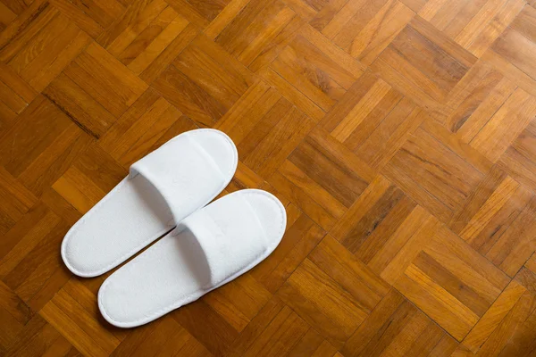 Dvojice bílé pantofle na dřevěnou podlahu — Stock fotografie